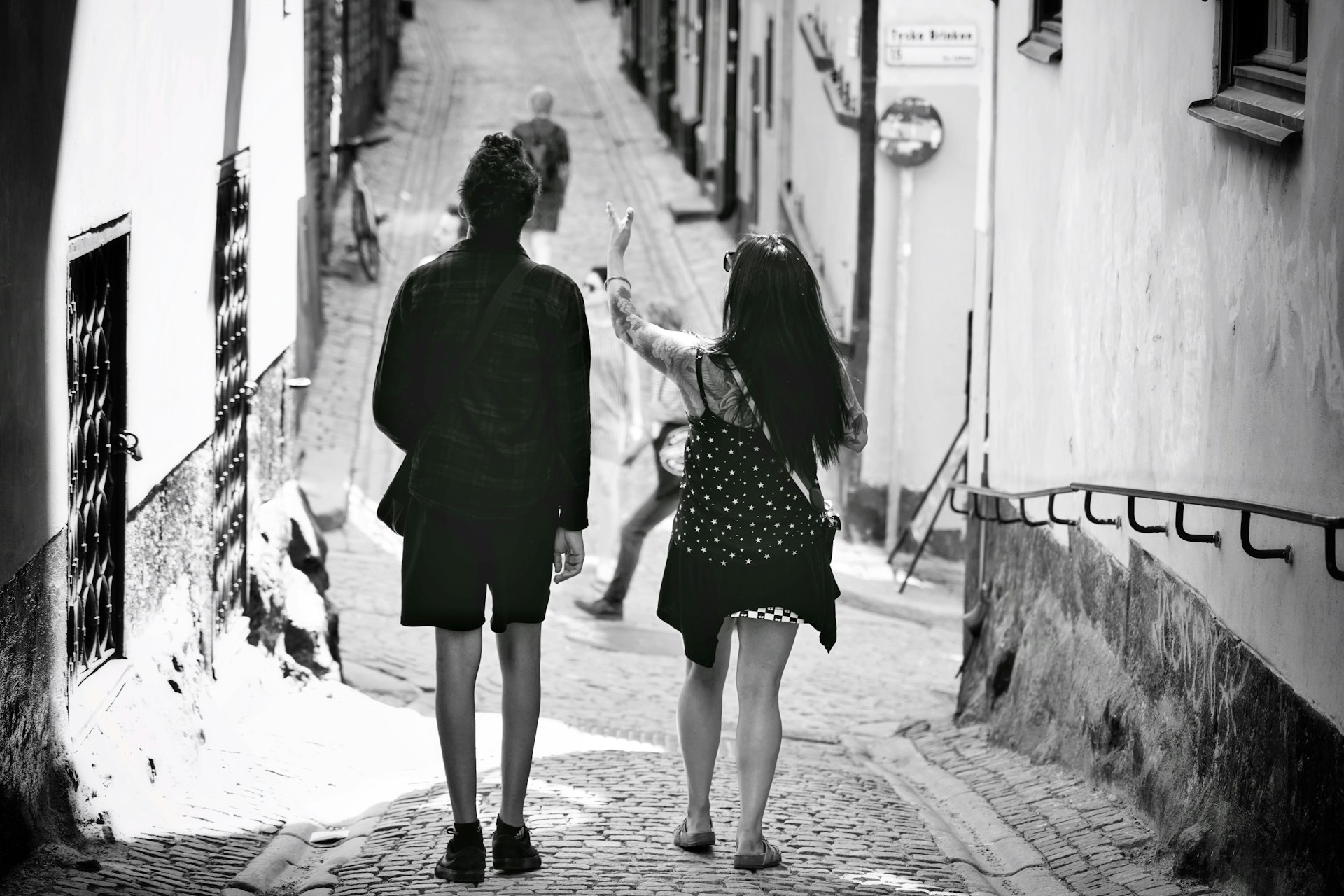 grayscale photo of 2 women walking on sidewalk